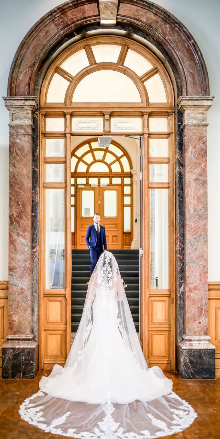 BackofdresswithlaceveilstoodinWaterhalldoowrwaywithGroom 768x1529