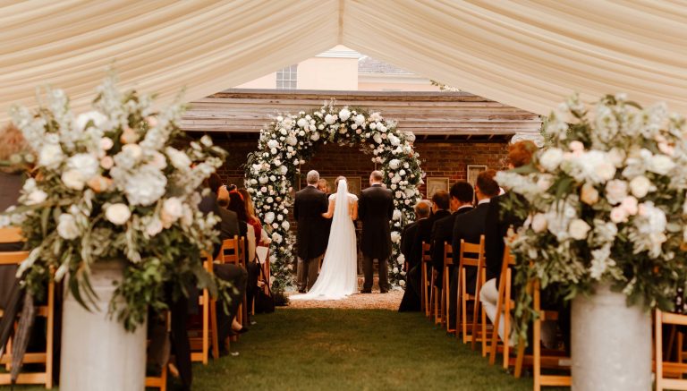 Bignor Park Weddings Greek Loggia Formal Gardens flower arch 2700x1536 1 768x437